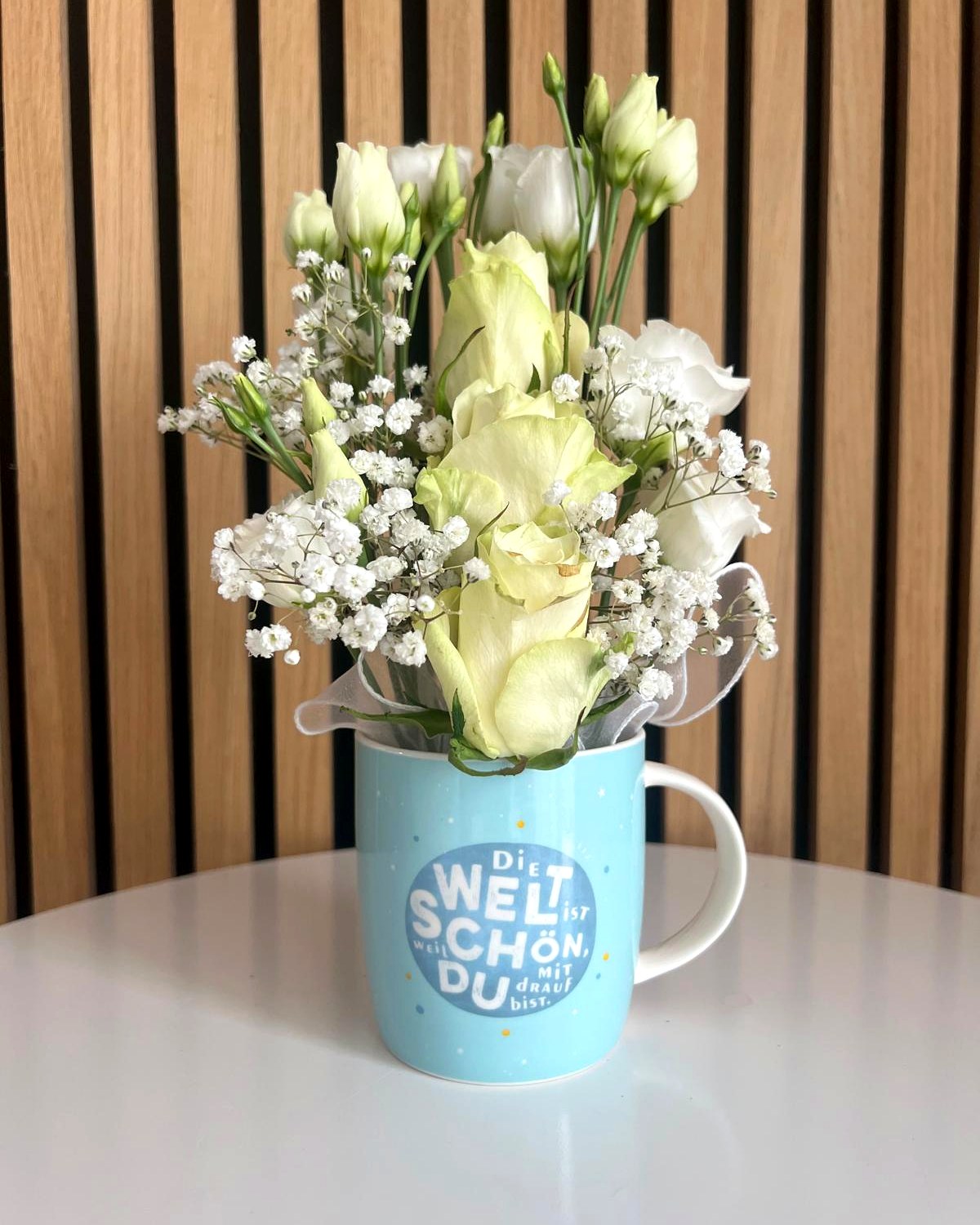 Weisse Rosen und Lisianthus in Tasse «Die Welt ist schön» – Blumengeschenk von TIKIS