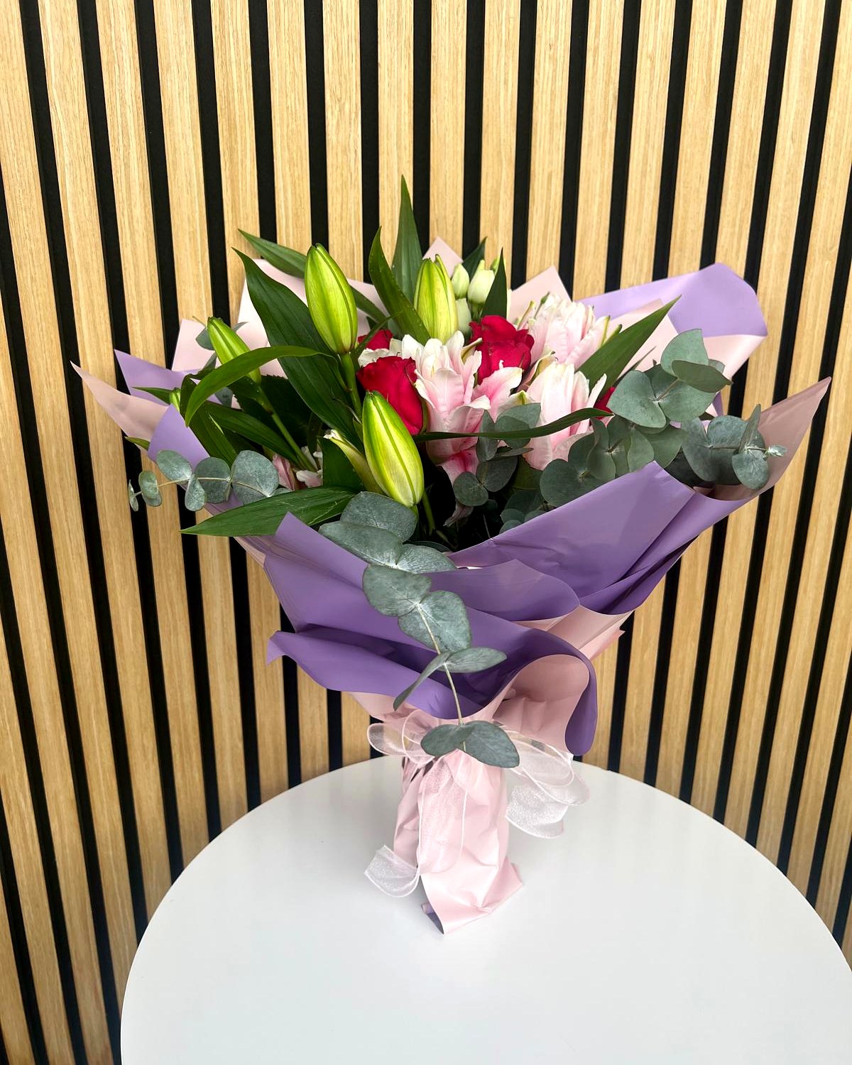 Blumenstrauss mit Lilien, pinken Rosen und Eukalyptus in lila Verpackung – TIKIS